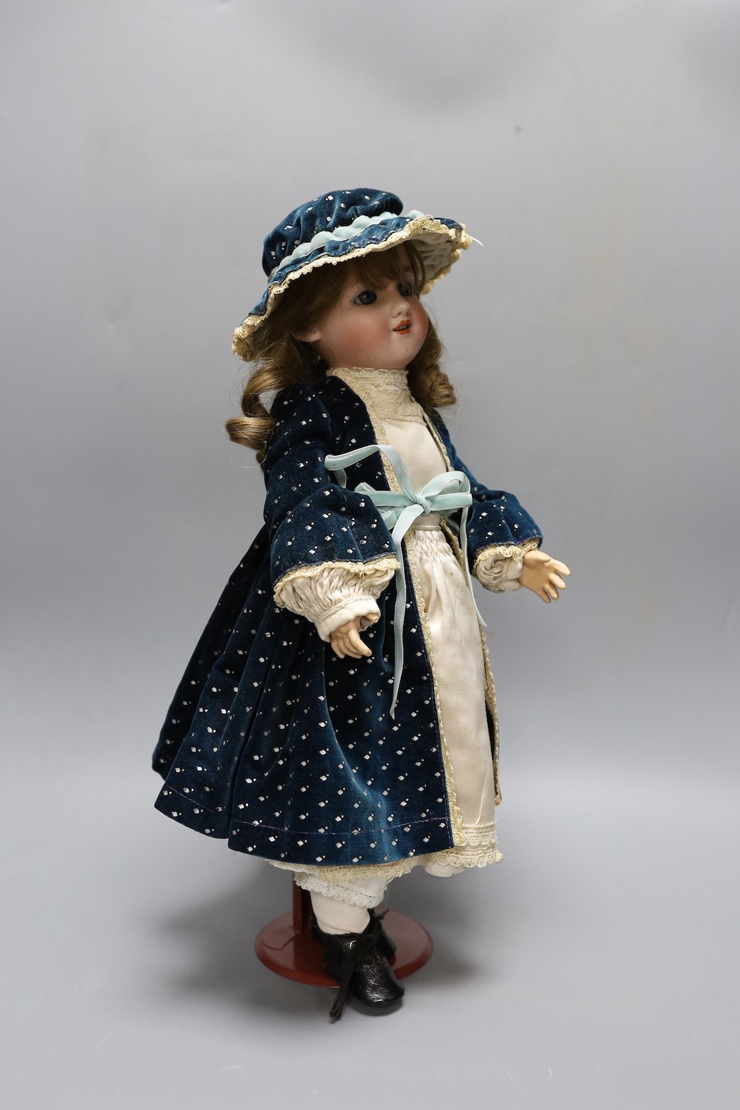 A Simon & Halbig doll, cream satin dress and blue velvet coat, open mouth, 44.5 cms high.